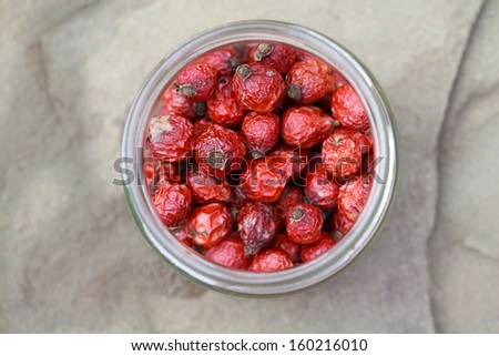 dried rose hips in a jar on a stone table, selective focus, some berries in focus, some are not