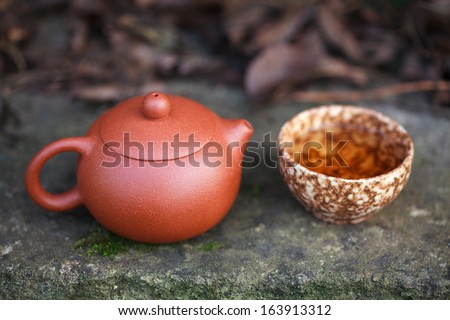 Traditional chinese tea ceremony accessories (tea pot and tea cup) on the old stone table, selective focus