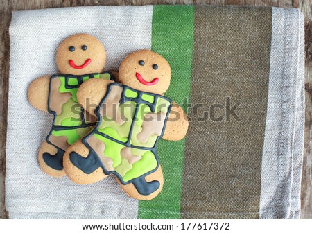 Two homemade Gingerbread men in protective khaki uniforms on Defender of the Fatherland Day, selective focus on right man, place for text