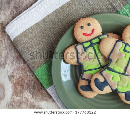 Two homemade Gingerbread men in protective khaki uniforms on Defender of the Fatherland Day, selective focus on left man, place for text