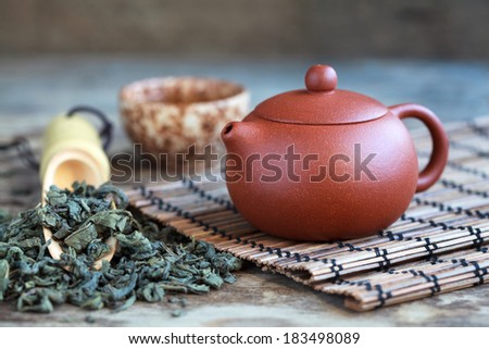 Traditional chinese tea ceremony accessories: tea pot, cup and green tea on the wooden table, selective focus
