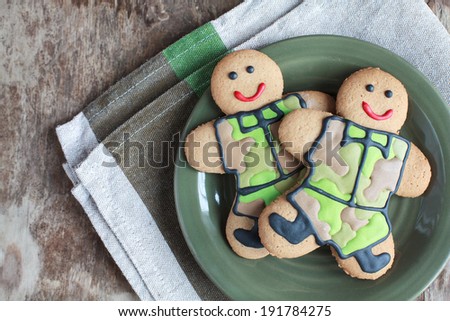 Two homemade Gingerbread men in protective khaki uniforms on Defender of the Fatherland Day, selective focus