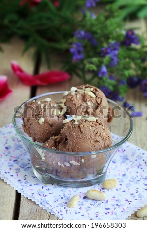 Homemade chocolate ice cream with peanut butter, sprinkle with chopped peanuts in a glass bowl on a wooden table. Selective focus
