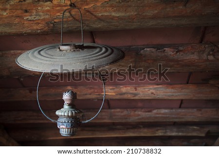 Rarity dusty kerosene lamp hanging under the ceiling in an old rustic attic, selective focus, space for text