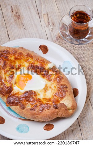 Ajarian khachapuri (traditional Georgian cheese pastry) with baked egg on wooden table