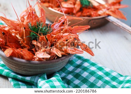 Copper frying pan with red boiled crawfish on a wooden table in rustic style, close-up, selective focus on some crawfish