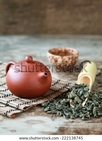 Traditional chinese tea ceremony accessories: tea pot, cup and green tea on the wooden table, selective focus, toned