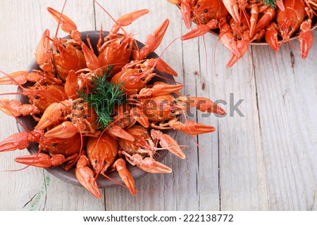 Old bowl with red boiled crawfish on a wooden table in rustic style, close-up, selective focus on some crawfishes