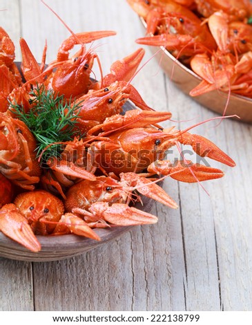 Old bowl with red boiled crawfish on a wooden table in rustic style, close-up, selective focus on one crawfish