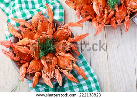 Old bowl with red boiled crawfish on a wooden table in rustic style, close-up, selective focus on some crawfishes