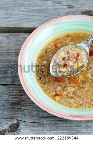 Vegetarian soup with quinoa, rice red, yellow lentils, corn, peppers, carrots, onions and celery on the wooden table in rustic style, macro