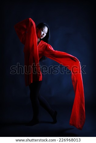 A beautiful young Chinese girl performs a traditional Chinese dance with long red sleeves, a red heart on a dark background, Contrast