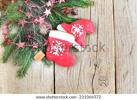 Homemade christmas gingerbreads painted as a red hat and boot of Santa with snowflake with with festive decoration on the wooden background with fir branches . Selective focus and place for text.