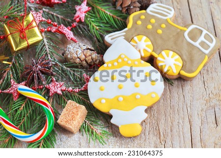 Homemade christmas gingerbreads painted as a yellow white Christmas tree toy and a train with festive decoration on the wooden background with fir branches. Selective focus and place for text.