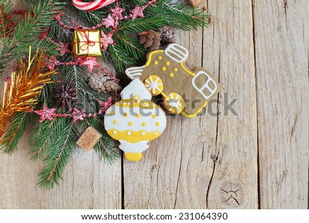 Homemade christmas gingerbreads painted as a yellow white Christmas tree toy and a train with festive decoration on the wooden background with fir branches. Selective focus and place for text.