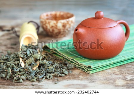 Traditional chinese tea ceremony accessories: tea pot, cup and green tea on the wooden table, selective focus. Toned