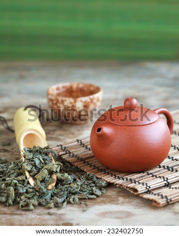 Traditional chinese tea ceremony accessories: tea pot, cup and green tea on the wooden table, selective focus. Toned
