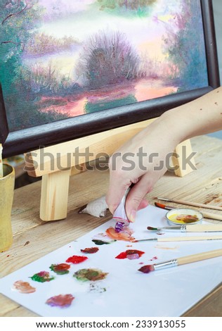 The artist paints a picture of the landscape using oily paints mounted on an easel. Selective focus