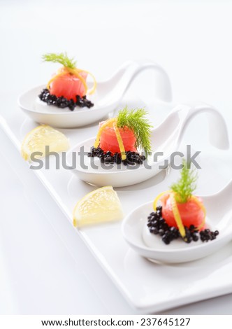 Appetizers in portion spoons of cream cheese, natural sturgeon black caviar, red salted salmon and dill on white background. Selective focus on the middle