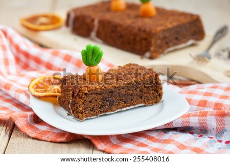 A piece of homemade carrot cake with nuts, decorated with marzipan carrots. Selective focus