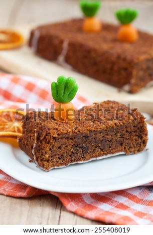 A piece of homemade carrot cake with nuts, decorated with marzipan carrots. Selective focus
