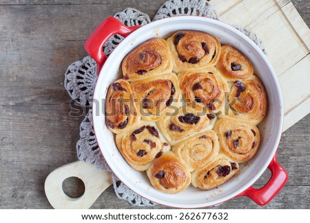 Traditional English buns Chelsea with dried cranberries and cinnamon on wooden table, selective focus and space for text