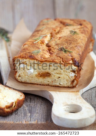 Savory loaf cake with parmesan cheese, feta cheese, figs and dry rosemary on a wooden table in rustic style. Selective focus.