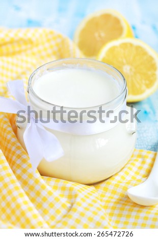 Homemade yogurt in small glass jar on a blue table, selective focus