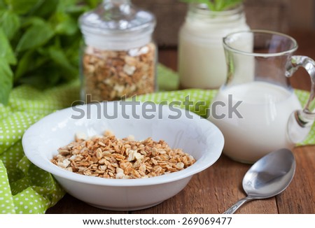 Breakfast: homemade granola in a white plate and yogurt with jam on a wooden table. Selective focus.