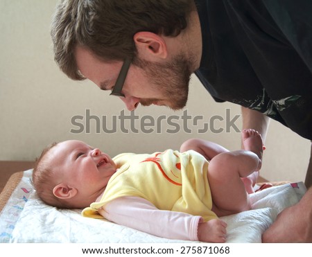Dad is going to change a diaper to his small smiling baby, selective focus