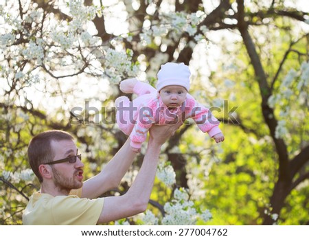 Dad playing with his baby daughter, he turns her around himself, selective focus on baby\'s face