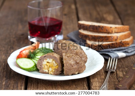 Traditional Russian cuisine - homemade meat patties (zrazy) stuffed with chopped eggs and onion on a wooden table. Rustic style and selective focus.