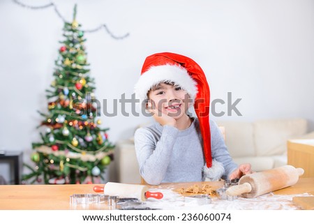 Little cute boy sitting and in front of the table with ginger cookies leaning on his arm