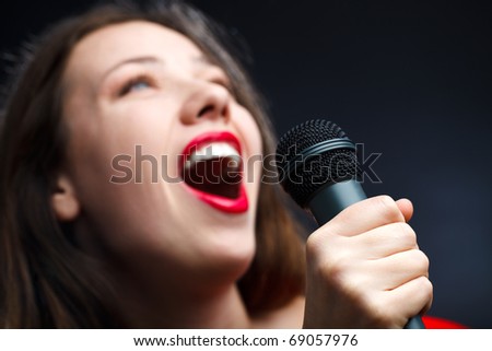 Woman sing over dark background. focused on hand.