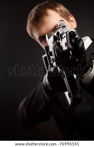 Man with gun over gradient gray. Focused on aim.
