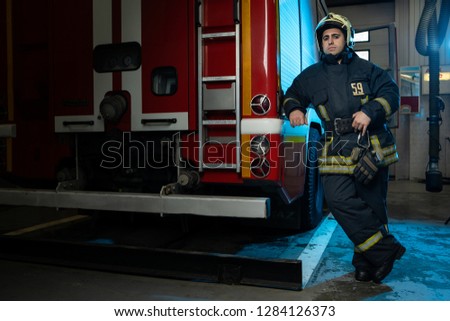 Full-length picture of man firefighter at fire truck