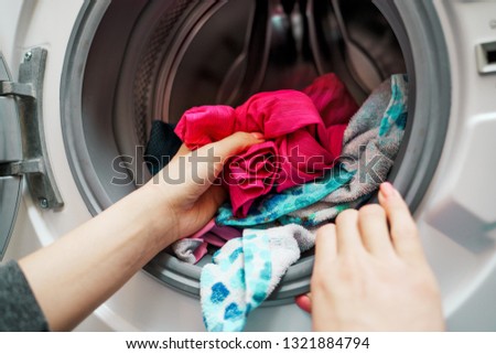 Image of female hands putting dirty clothes in washing machine