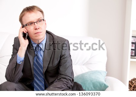 Attractive man sitting on sofa and speaking on the telephone on white background
