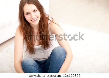 Smiling woman sitting on floor at home in living room