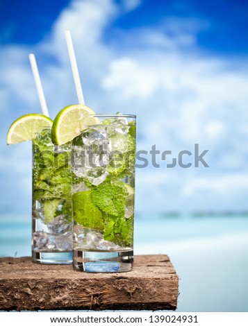 Cocktail mojito ice lemon straws in tropical beach Islands against a background