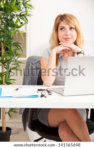 happy business woman sitting, thinking and working on laptop computer at office