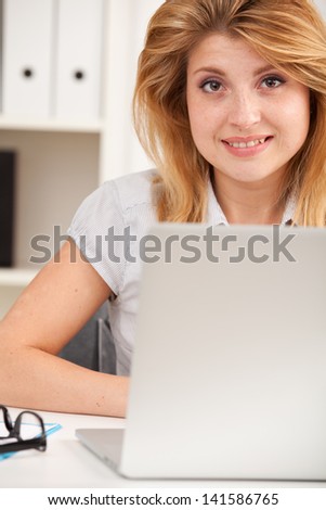 Closeup smiling office worker in front of laptop computer sitting in the office