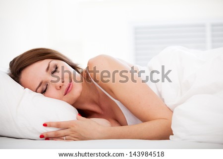 Portrait Of A Peaceful Beautiful Woman Sleeping In Bed Resting And Happy At Home Over White
