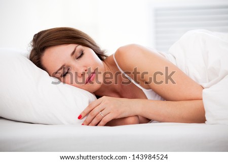 Portrait of a peaceful beautiful woman sleeping in bed resting and happy at home over white