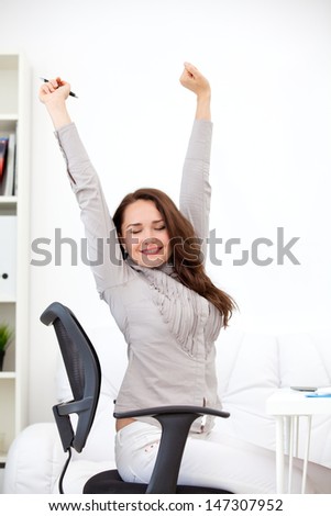 attractive, young woman stretching at her workplace and smiling in the office