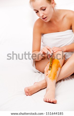 epilation: sitting woman remove with wax hair over white