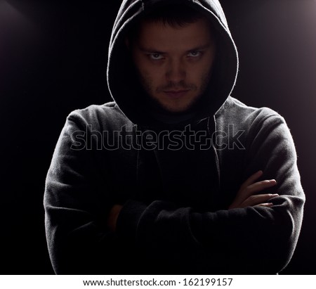 Silhouette of man in the hood or hooligan over dark