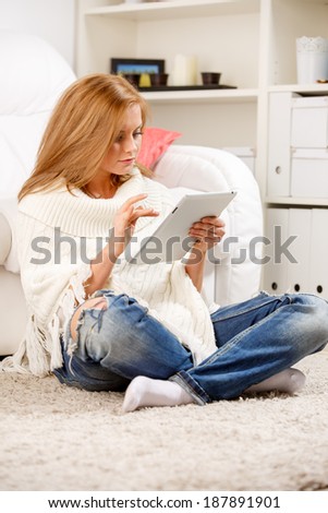 Young woman sitting on floor and using tablet at home