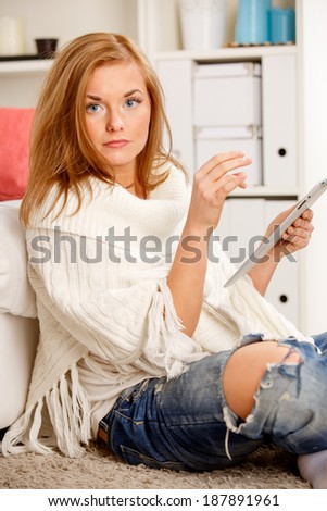 Young woman sitting on floor and using tablet at home