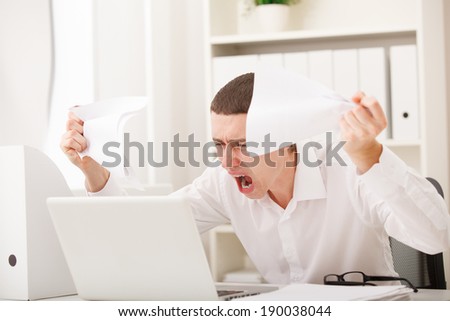 Angry businessman screaming against laptop in office